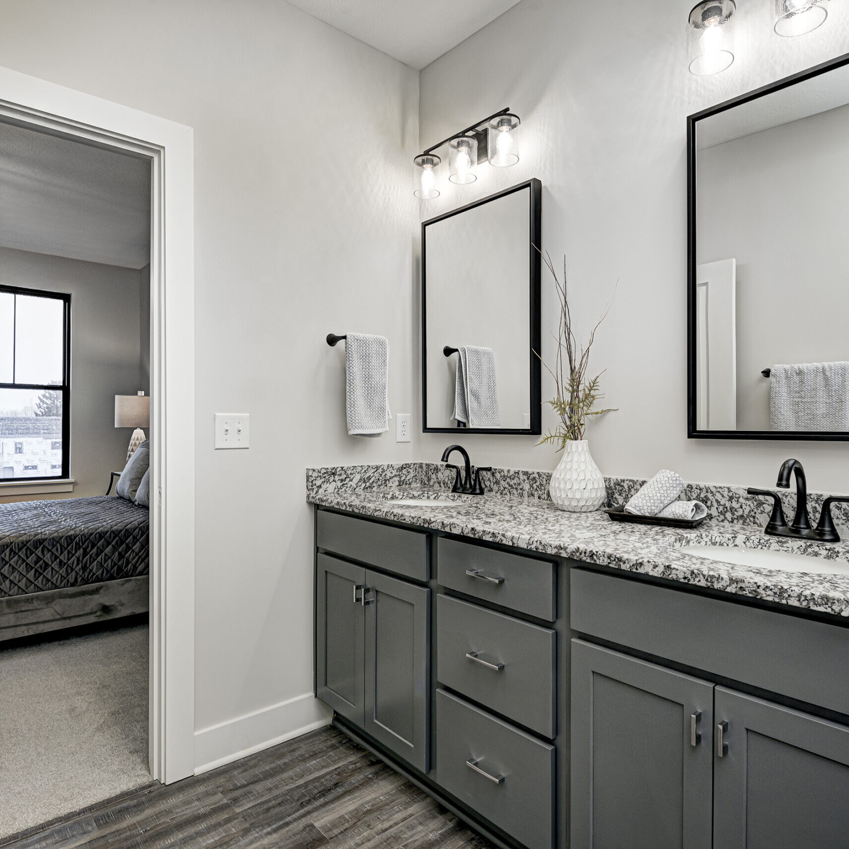 A bathroom with gray cabinets and granite counter tops, designed by a Custom Home Builder Carmel Indiana.