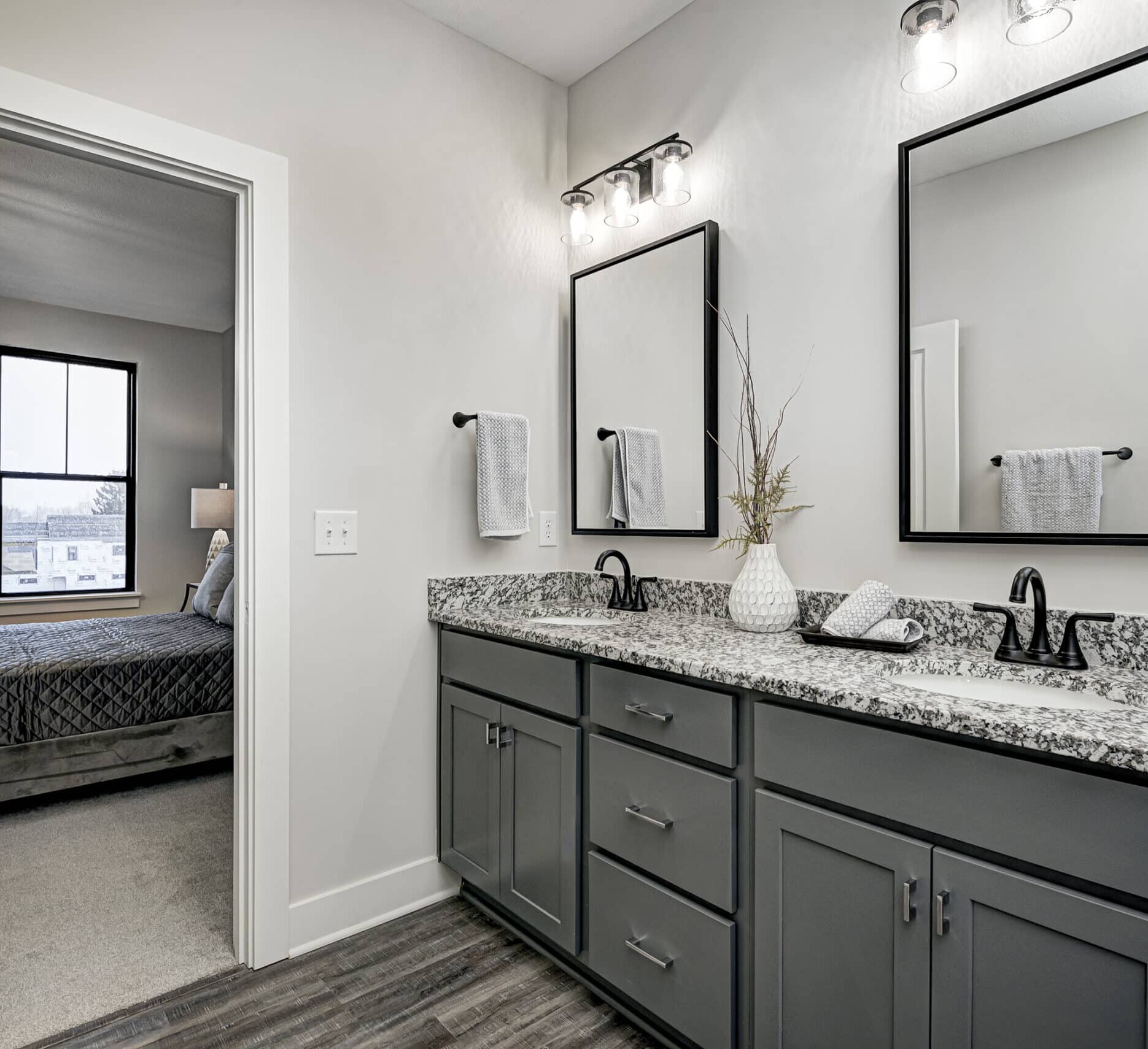 A bathroom with gray cabinets and granite counter tops, designed by a Custom Home Builder Carmel Indiana.
