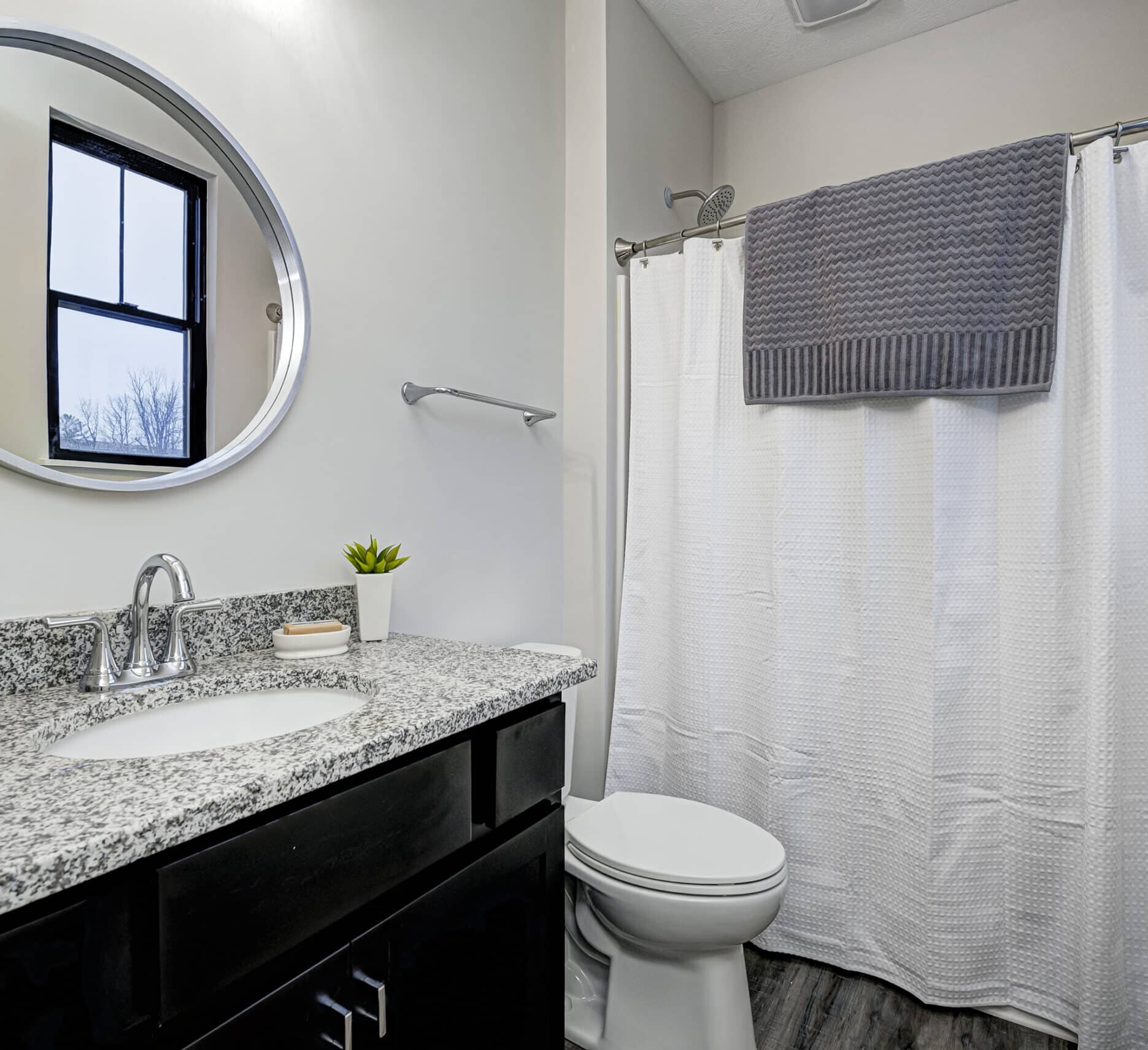 A custom bathroom with a black shower curtain and granite counter top.