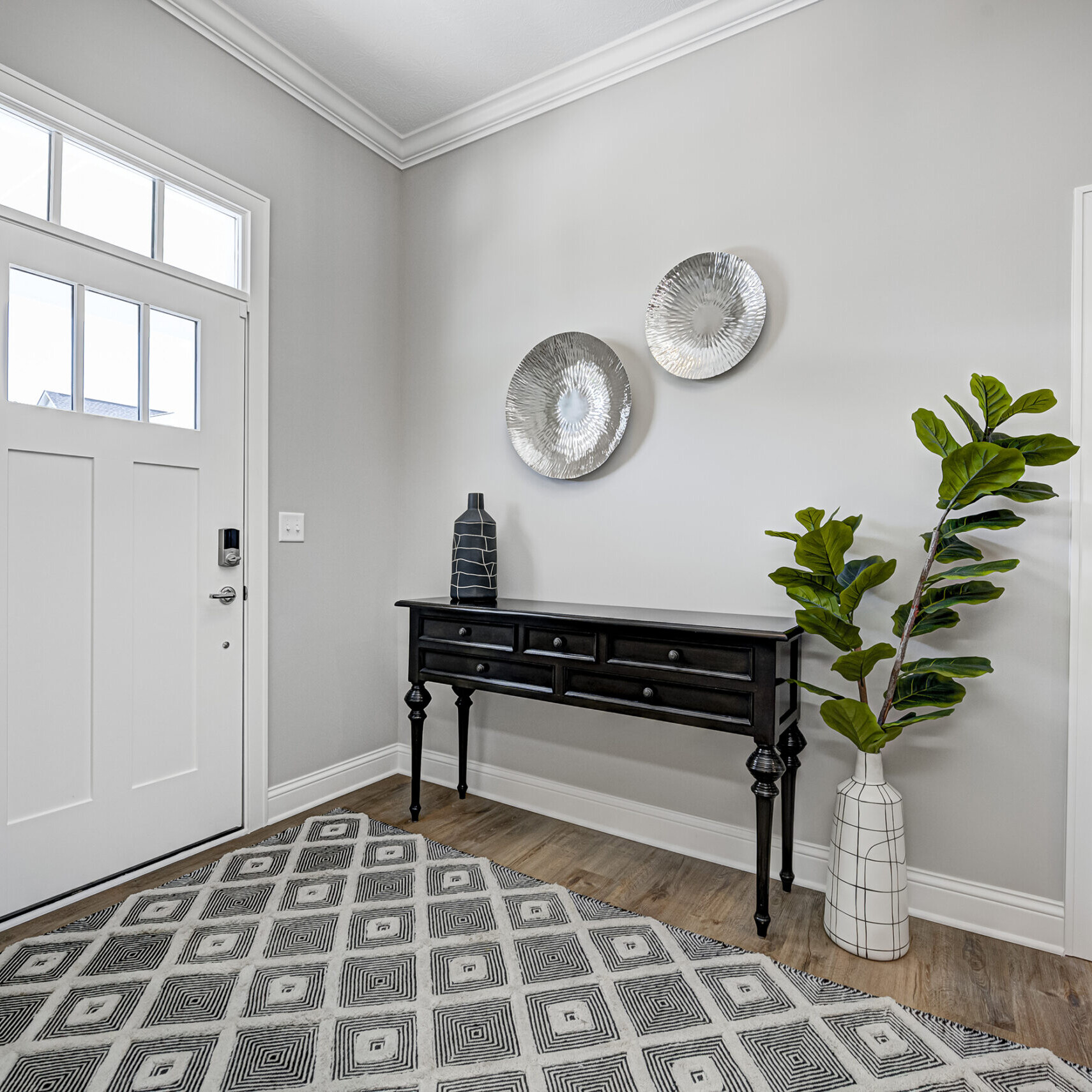 A custom home entryway with a gray rug and white door.