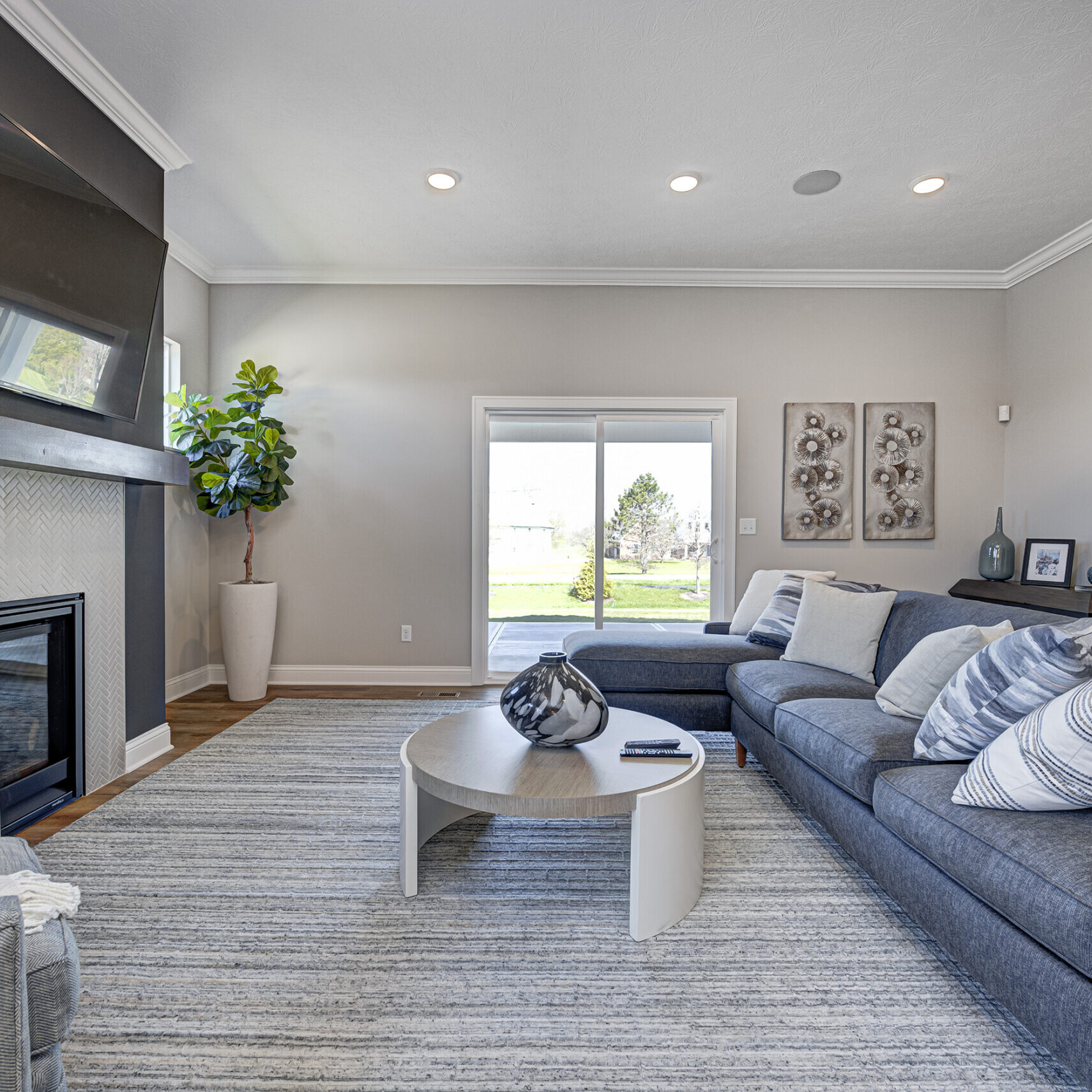 A living room with a gray couch and TV in a Custom Home Builder Fishers Indiana.