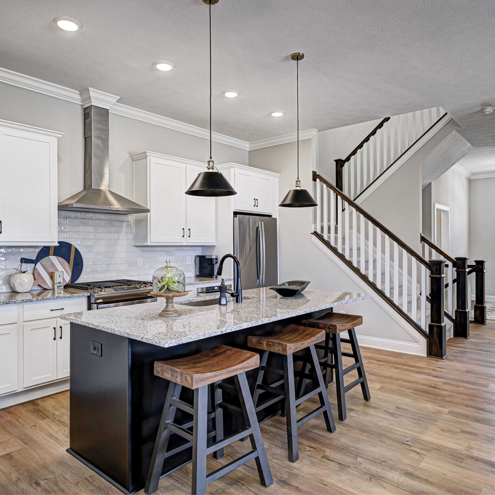 A Custom Home Builder Carmel Indiana with a kitchen featuring hardwood floors and a stairway.