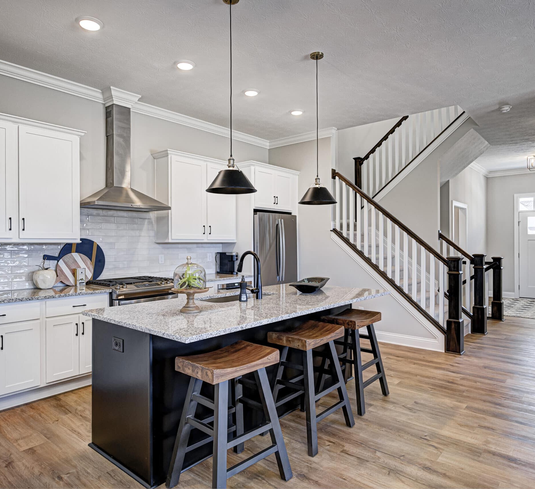 A Custom Home Builder Carmel Indiana with a kitchen featuring hardwood floors and a stairway.
