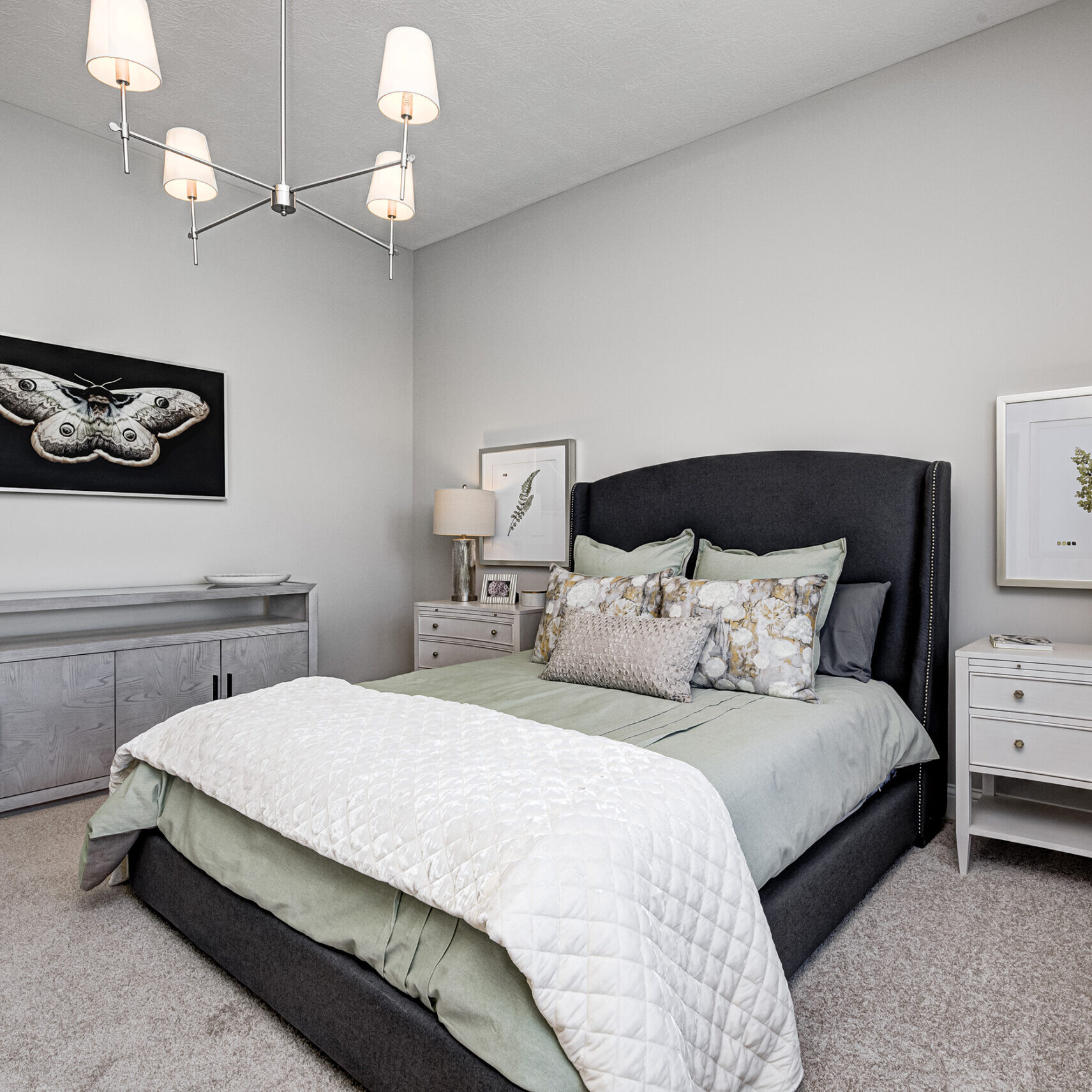 A bedroom with a gray bed and dresser, furnished by a Custom Home Builder in Indiana.