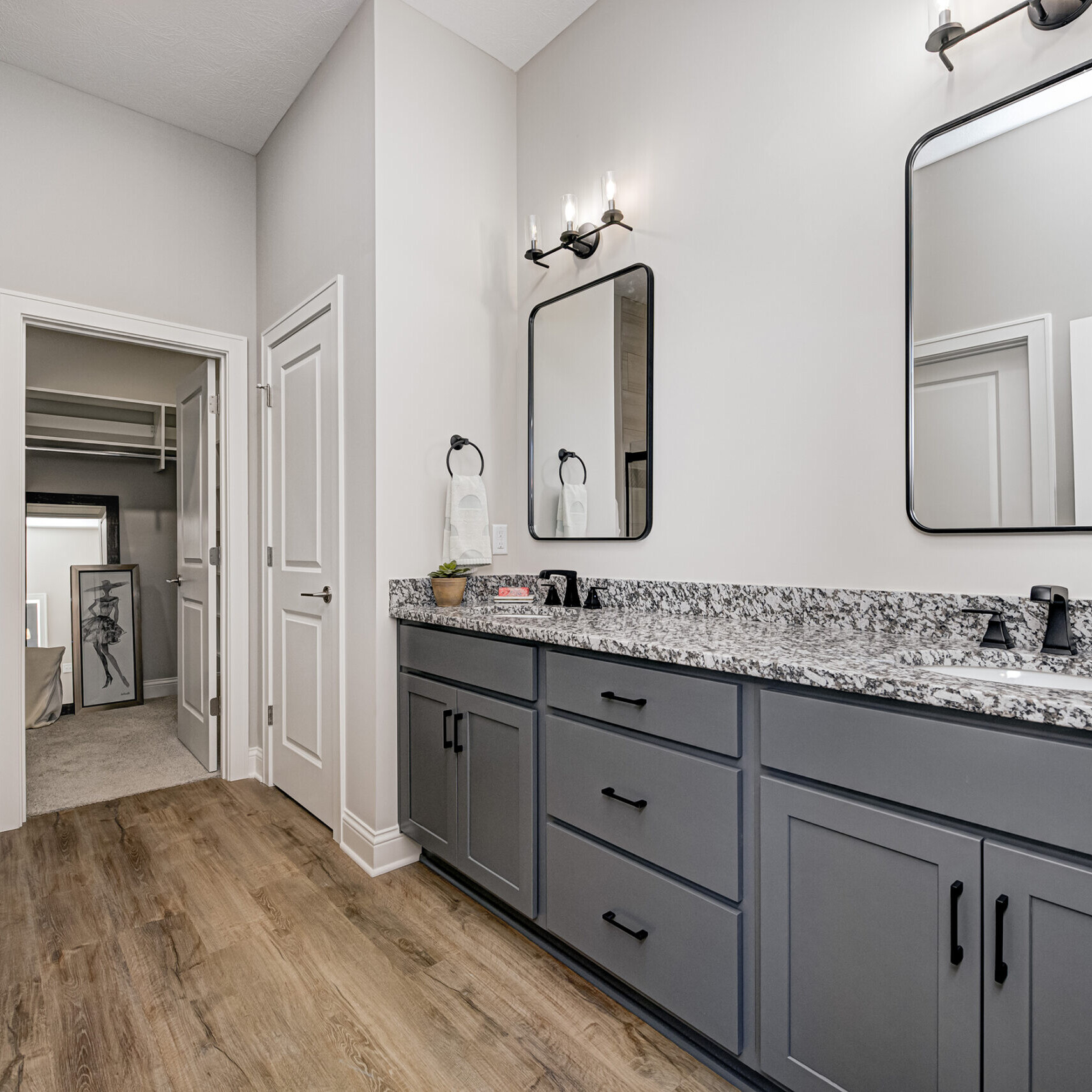 A bathroom with gray cabinets and hardwood floors in a custom home.