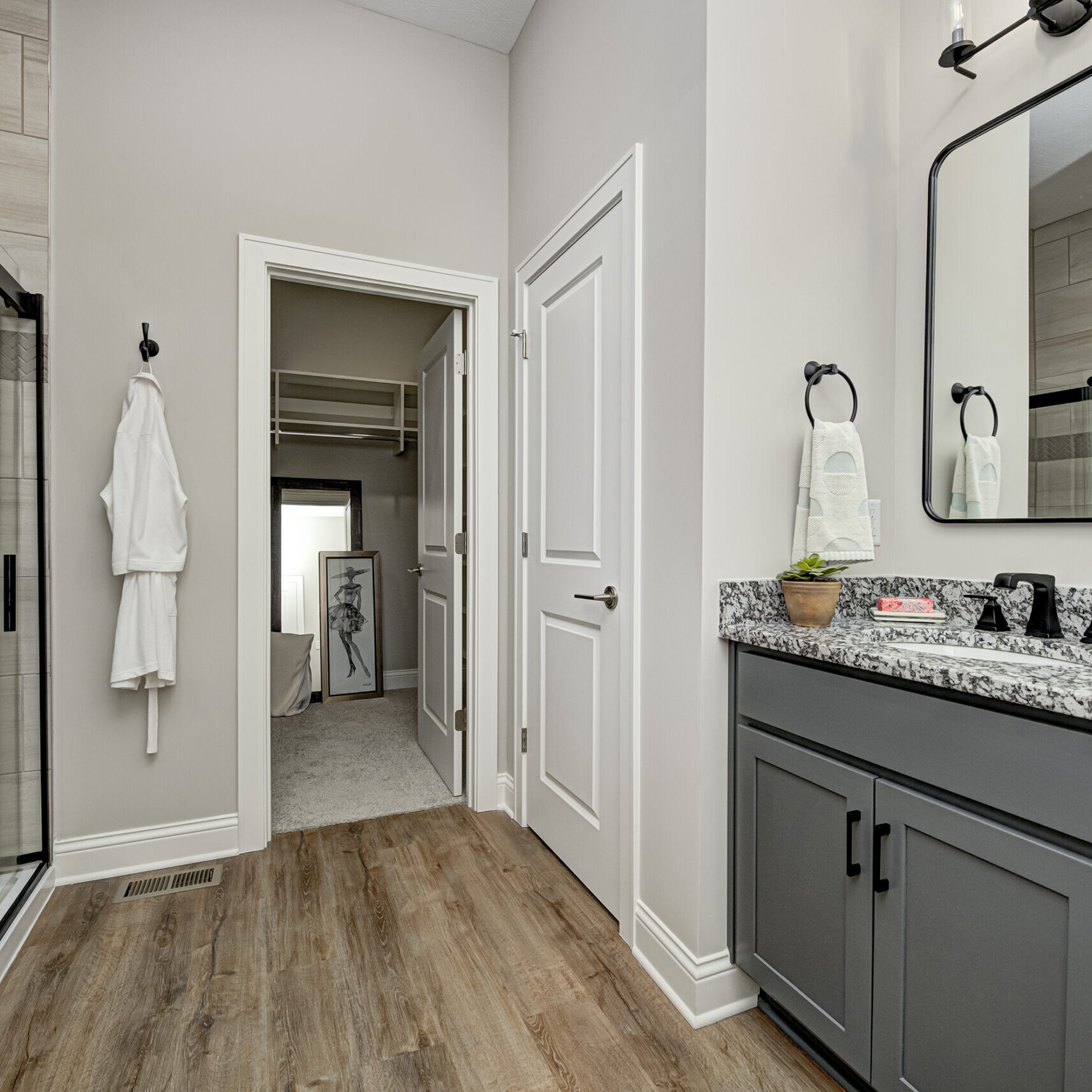 A bathroom with custom gray cabinets and a spacious walk-in shower.