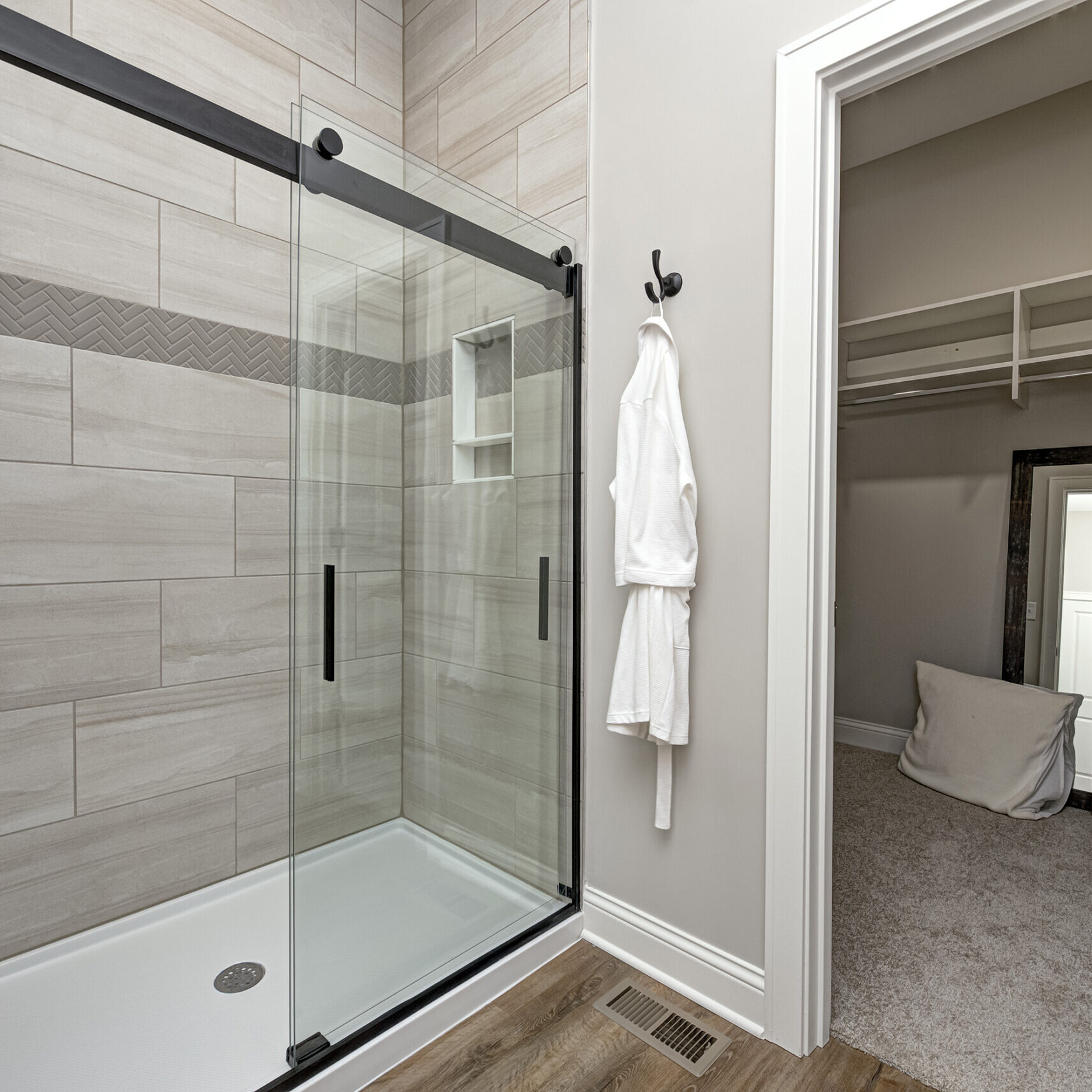A luxurious bathroom with a glass shower door and a spacious walk-in closet. Perfect for those seeking the finest in Custom Homes Westfield Indiana and Indianapolis Custom Homes. Experience the epitome of elegance