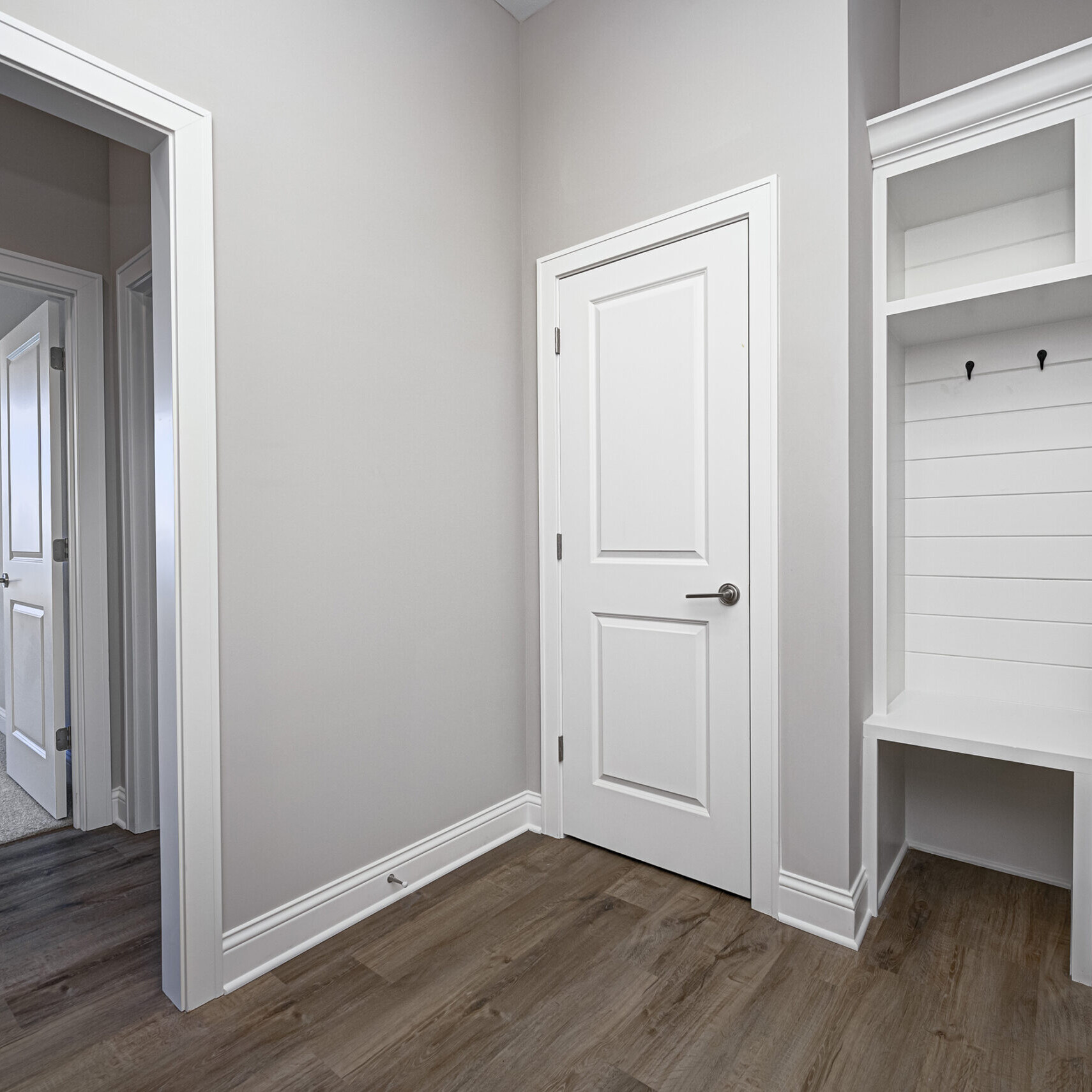 A custom hallway with a white door and wood floors in a home built by Custom Homes Westfield Indiana.