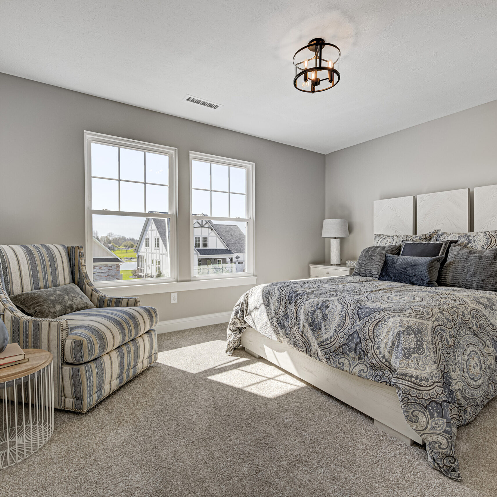 A custom-built bedroom in a Westfield, Indiana home featuring a bed, chair, and a window.