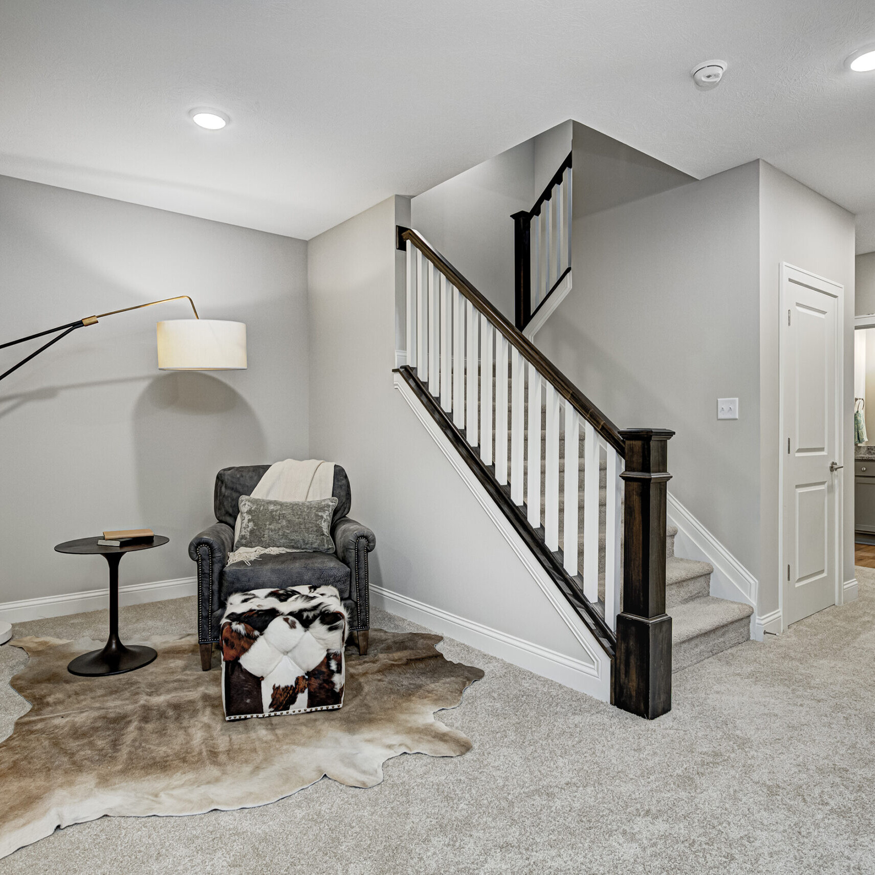 A custom home builder in Fishers, Indiana creates a stunning new home featuring a hallway adorned with a luxurious cowhide rug and an elegant stairway.