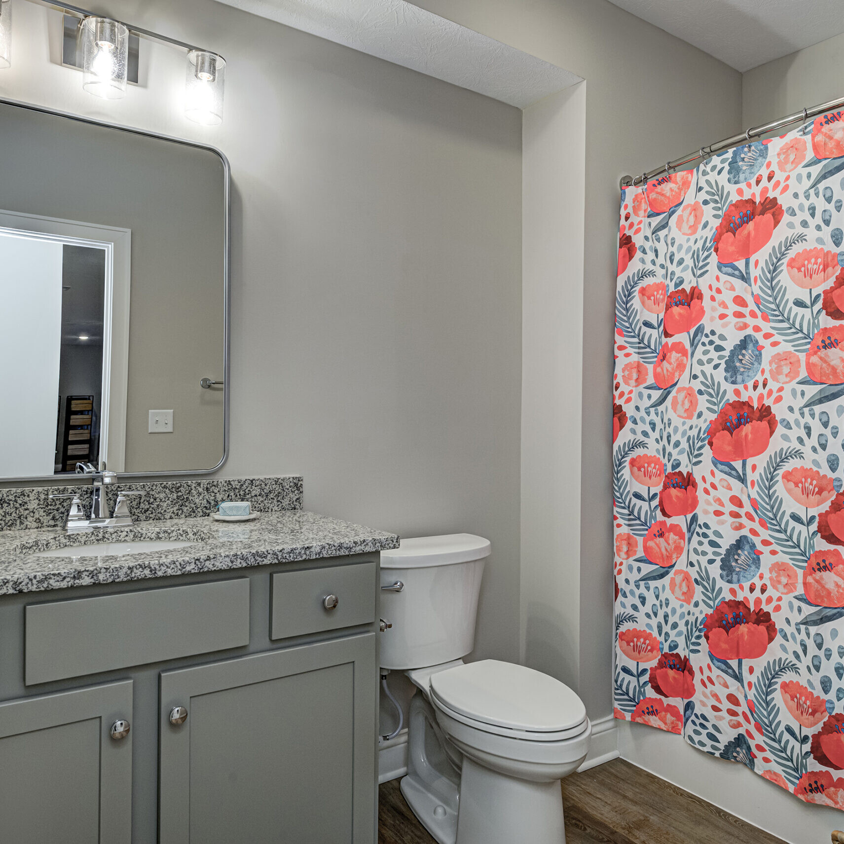 A bathroom with a floral shower curtain in a Custom Home in Westfield, Indiana.