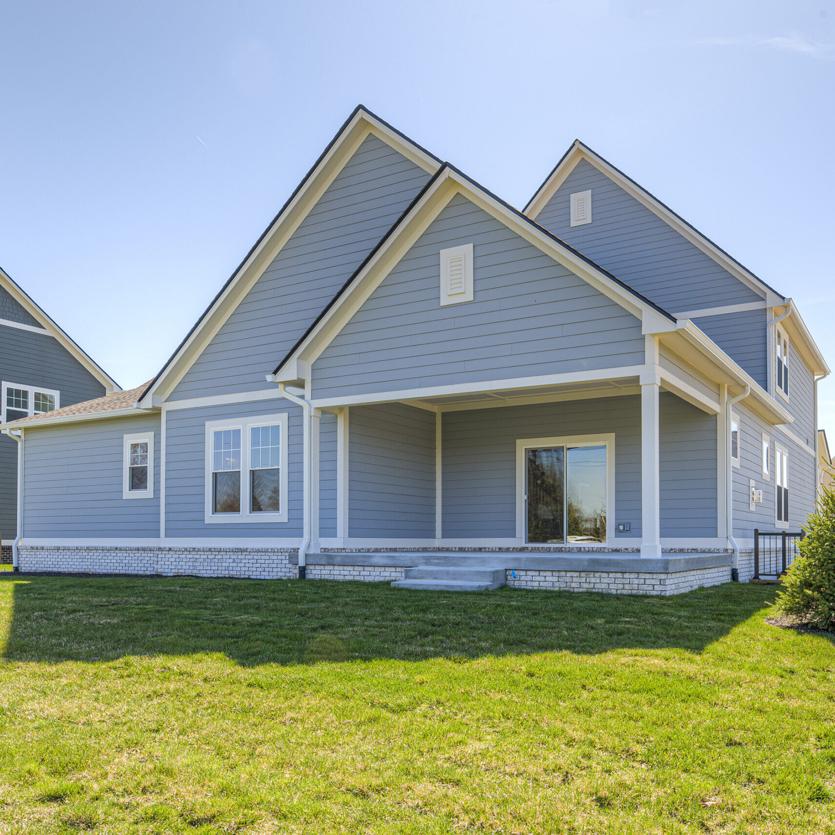 A new custom home with blue siding and a grassy yard in Fishers, Indiana.