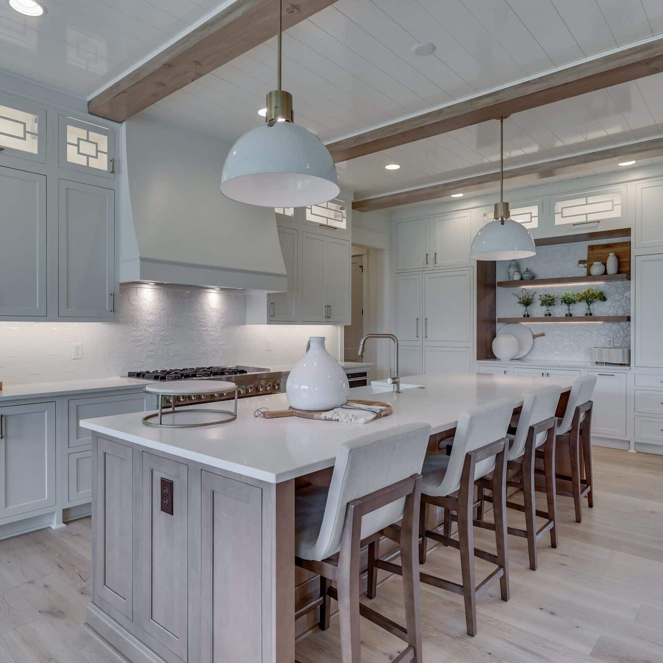A white kitchen with wood beams and a center island.