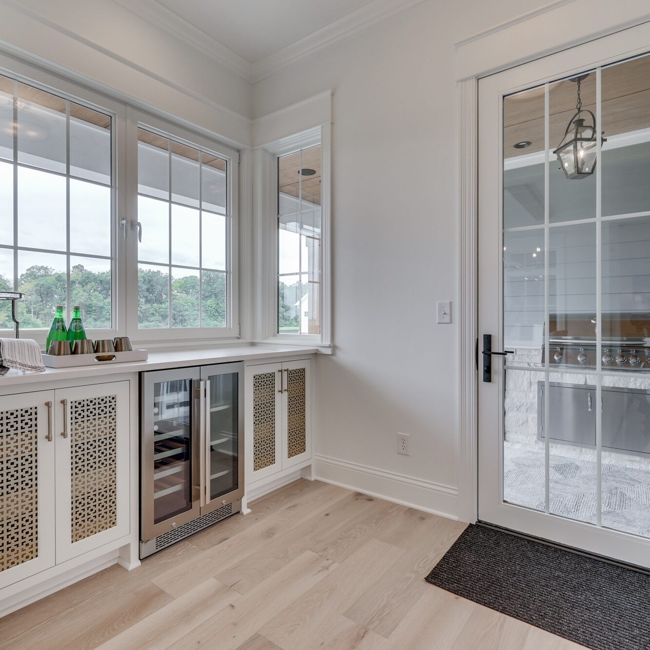 A white kitchen with a glass door and wood floors.