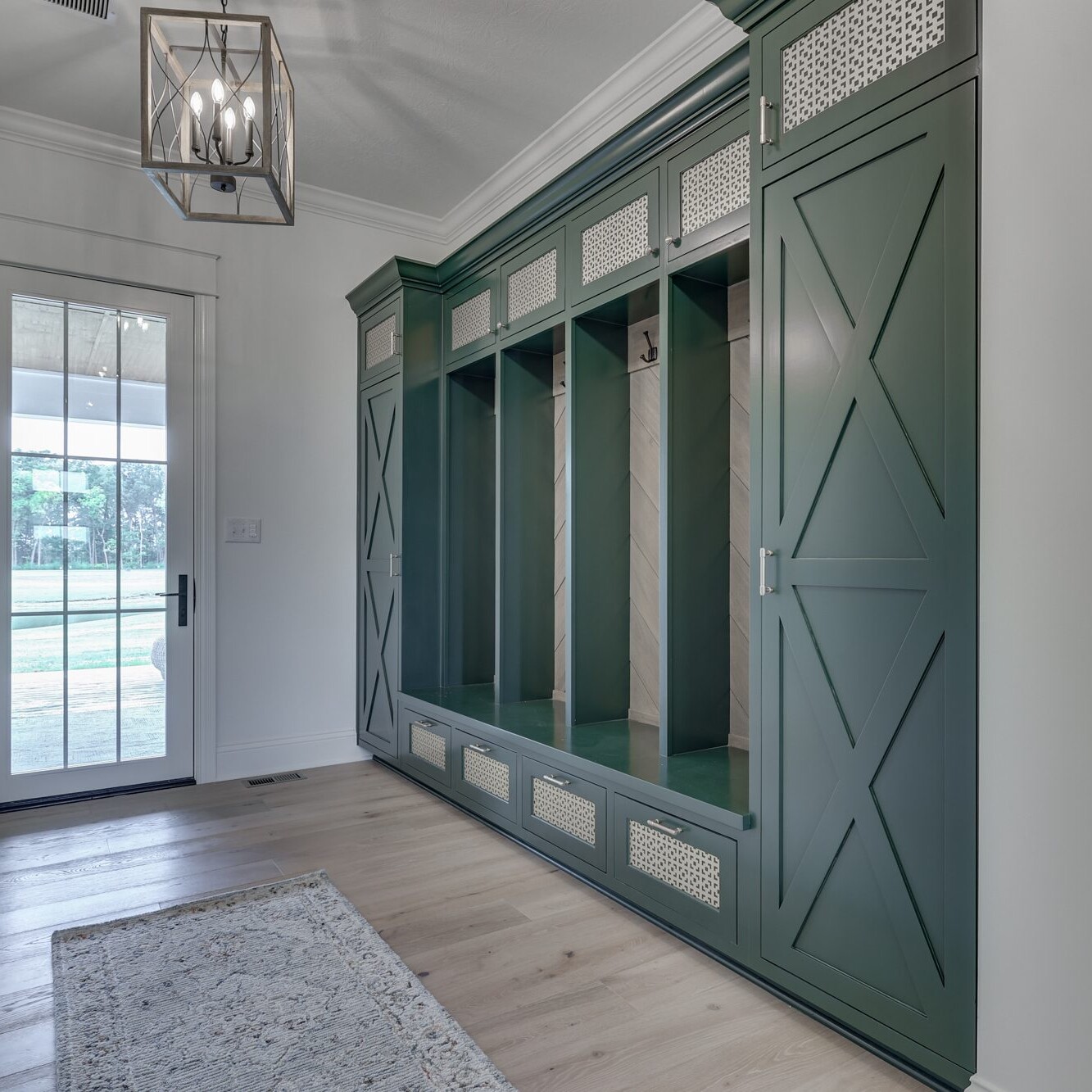 A green mudroom with wooden cabinets and a door.