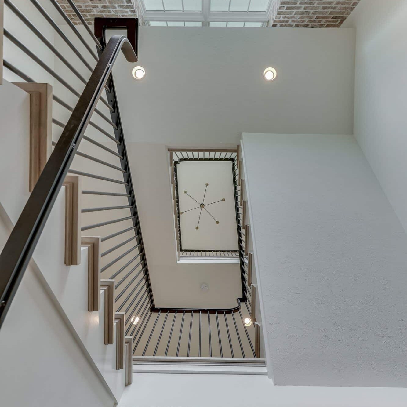 A white staircase with a skylight in the middle.