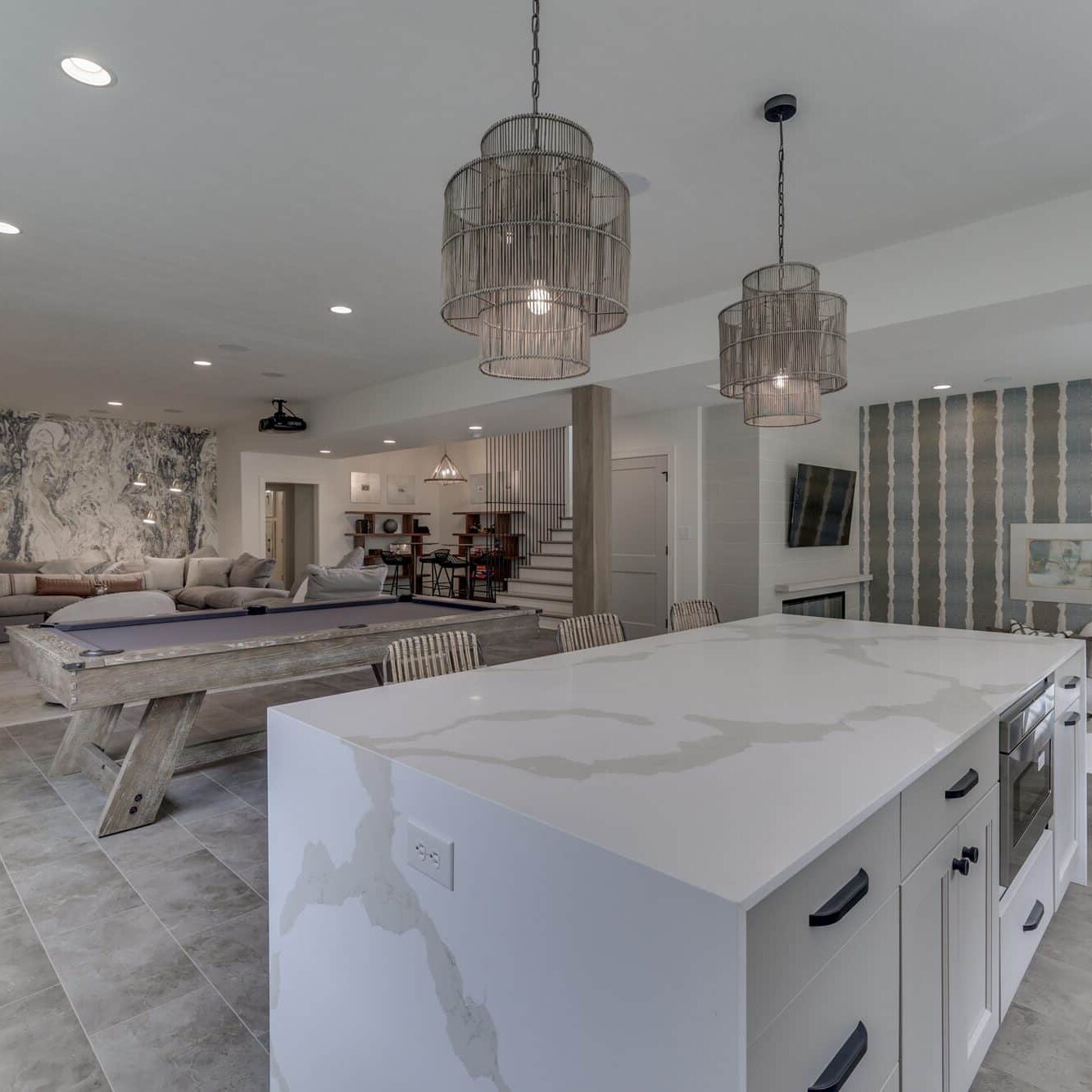 A white kitchen with marble counter tops and a pool table.