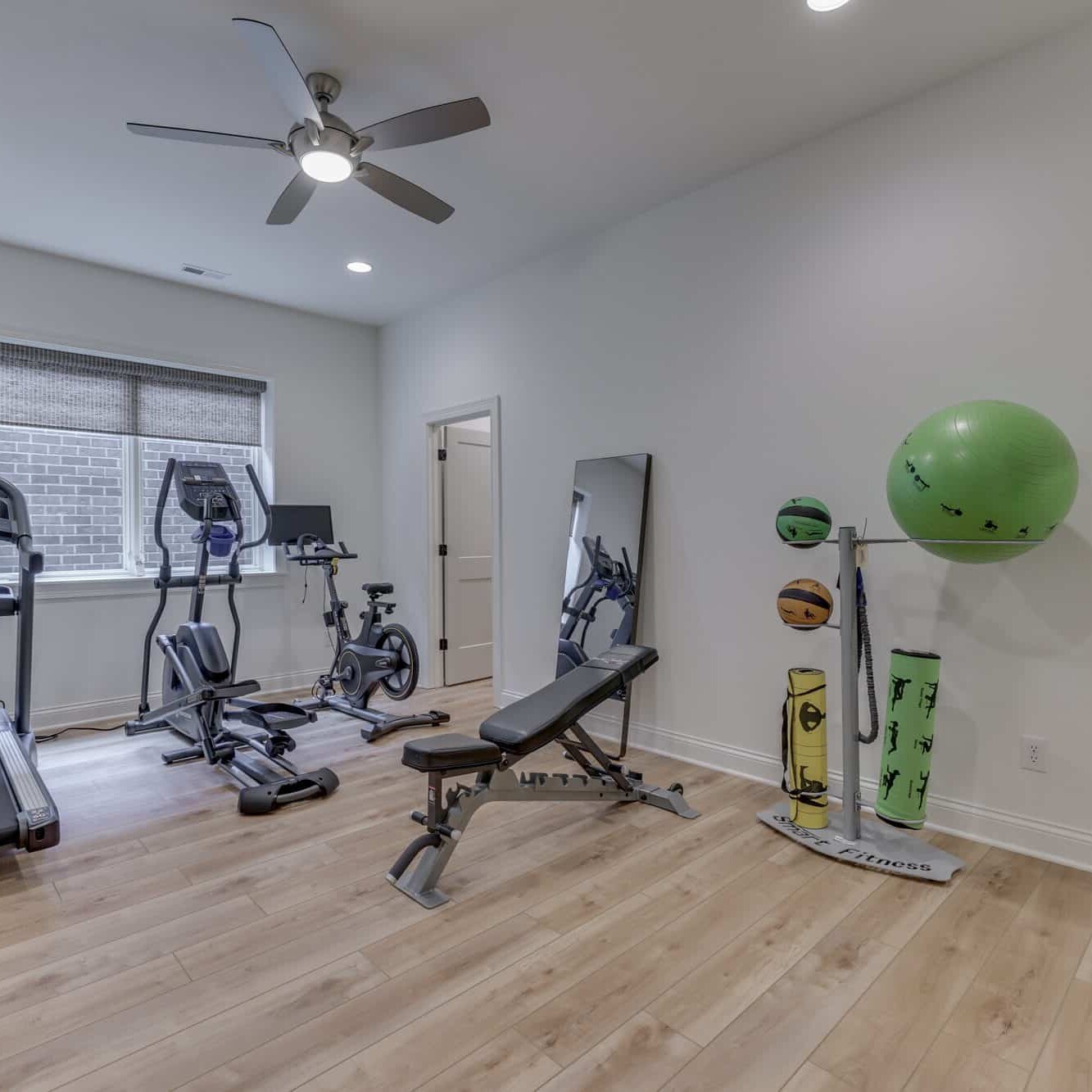 A gym room with exercise equipment and a fan.