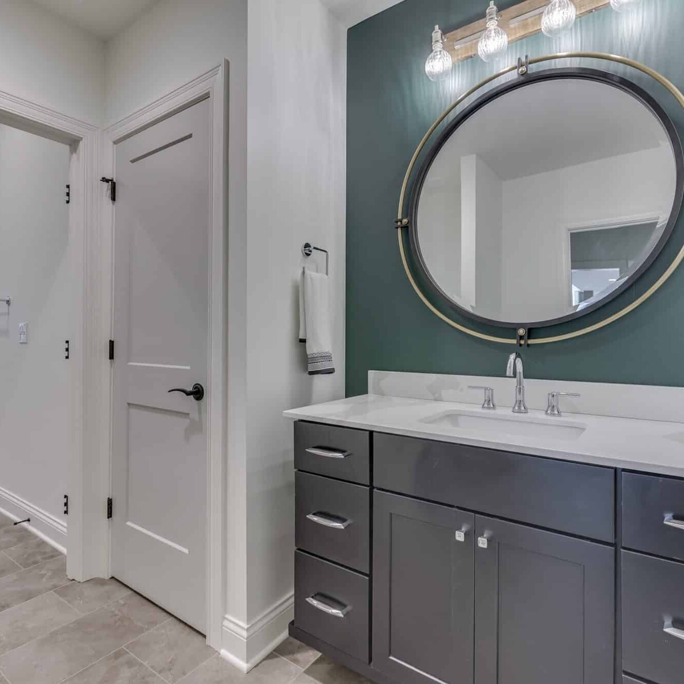 A bathroom with gray walls and a round mirror.