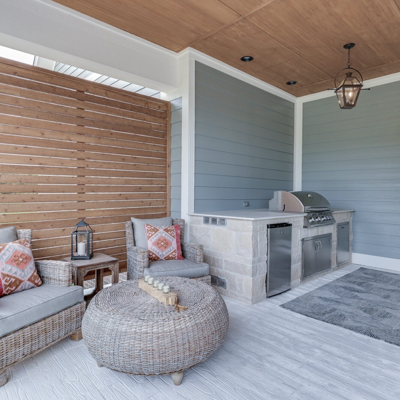 A porch with wicker furniture and a grill.