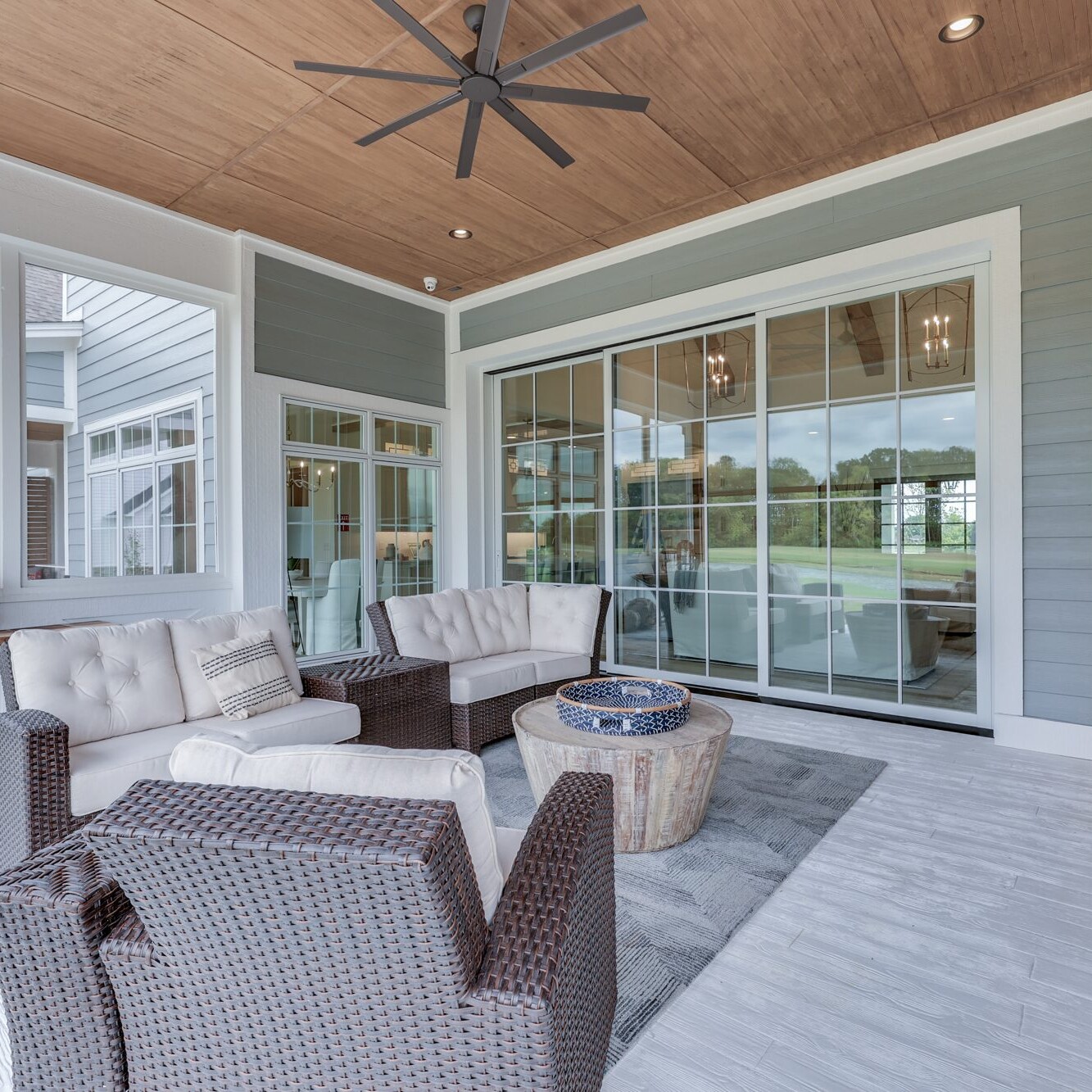 A covered porch with wicker furniture and a ceiling fan.