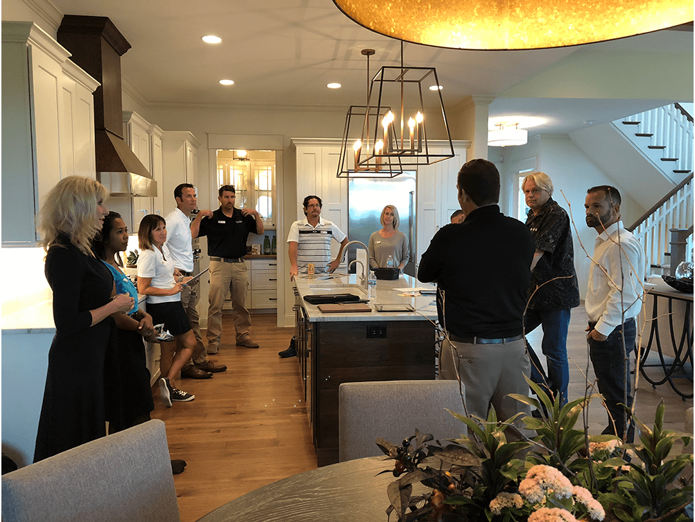 A group of people standing in a kitchen.