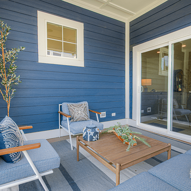 A blue and white patio with a table, chairs, and a sliding glass door.