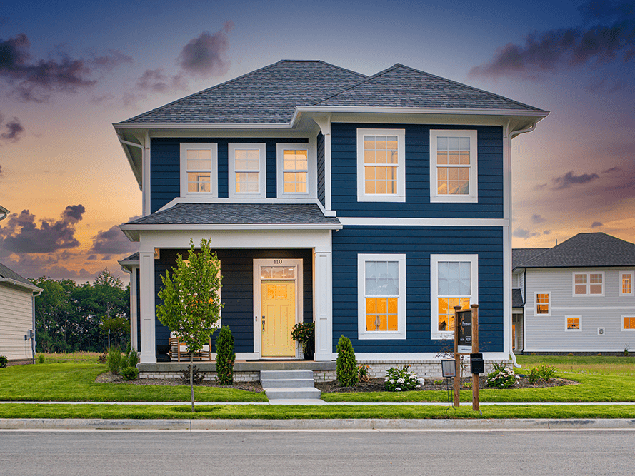 A custom blue house on a street at dusk, built by professional home builders.