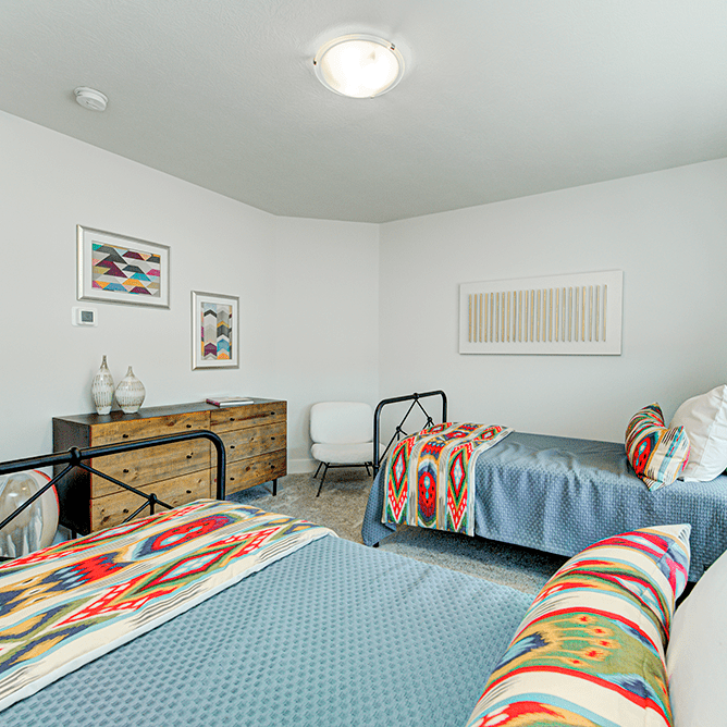 A bedroom with two beds and a dresser.