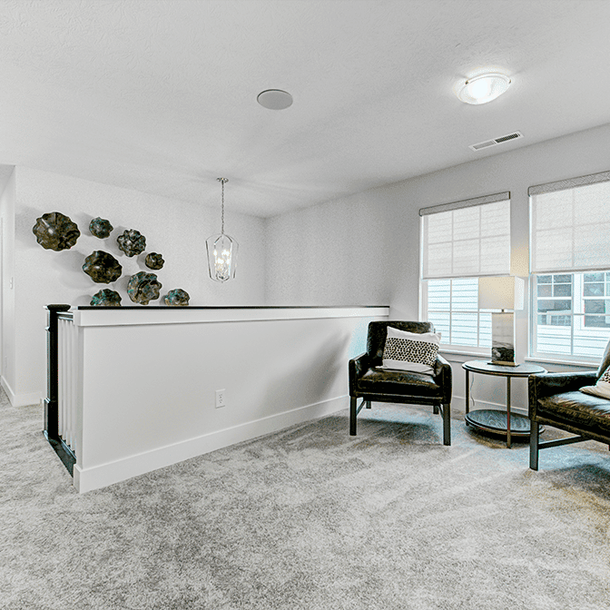 A living room with gray carpet and a chair.