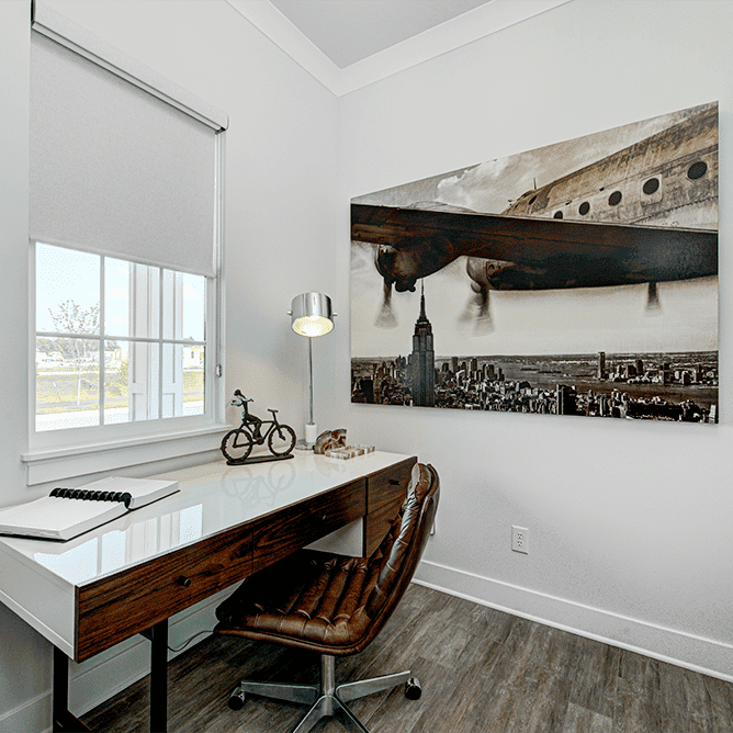A home office with a desk and a painting on the wall.