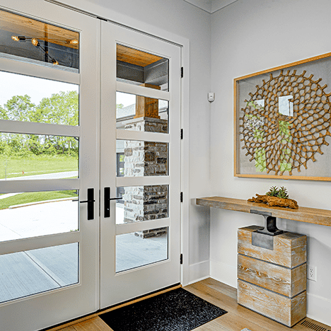 A white entryway with a wooden table and a mirror.