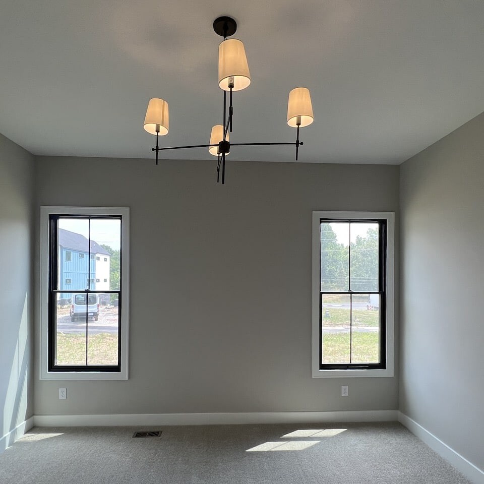 A custom-built home with two spacious windows overlooking the beautiful landscape, adorned with an elegant chandelier hanging from the ceiling.