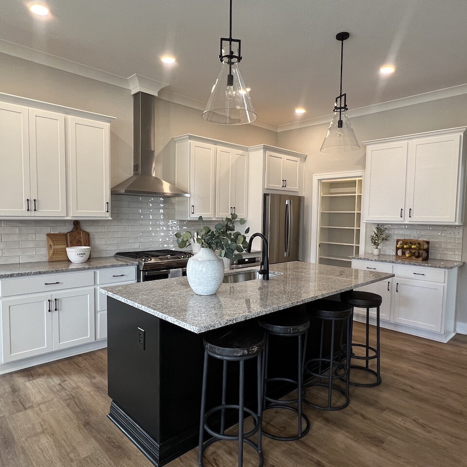 A kitchen with white cabinets and black counter tops, customized by a top-tier custom home builder in Westfield, Indiana.