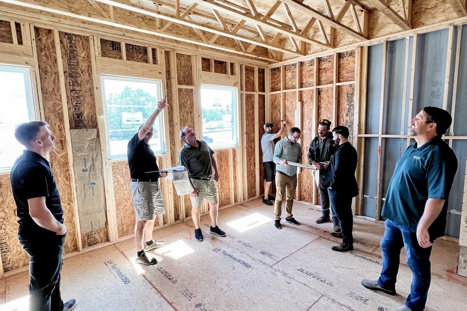 A group of people standing in a room with wood framing, guided by a Custom Home Builder in Carmel Indiana.