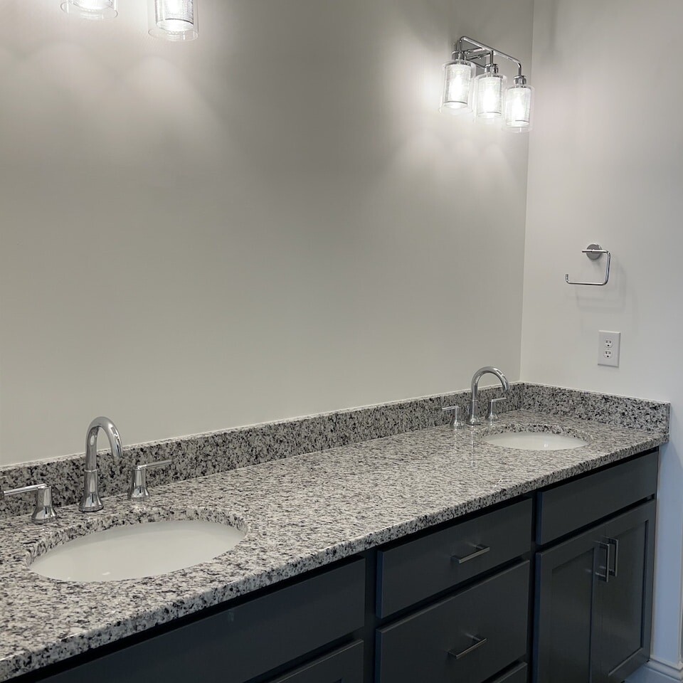 A bathroom with two sinks and granite counter tops, built by a Custom Home Builder in Carmel Indiana.