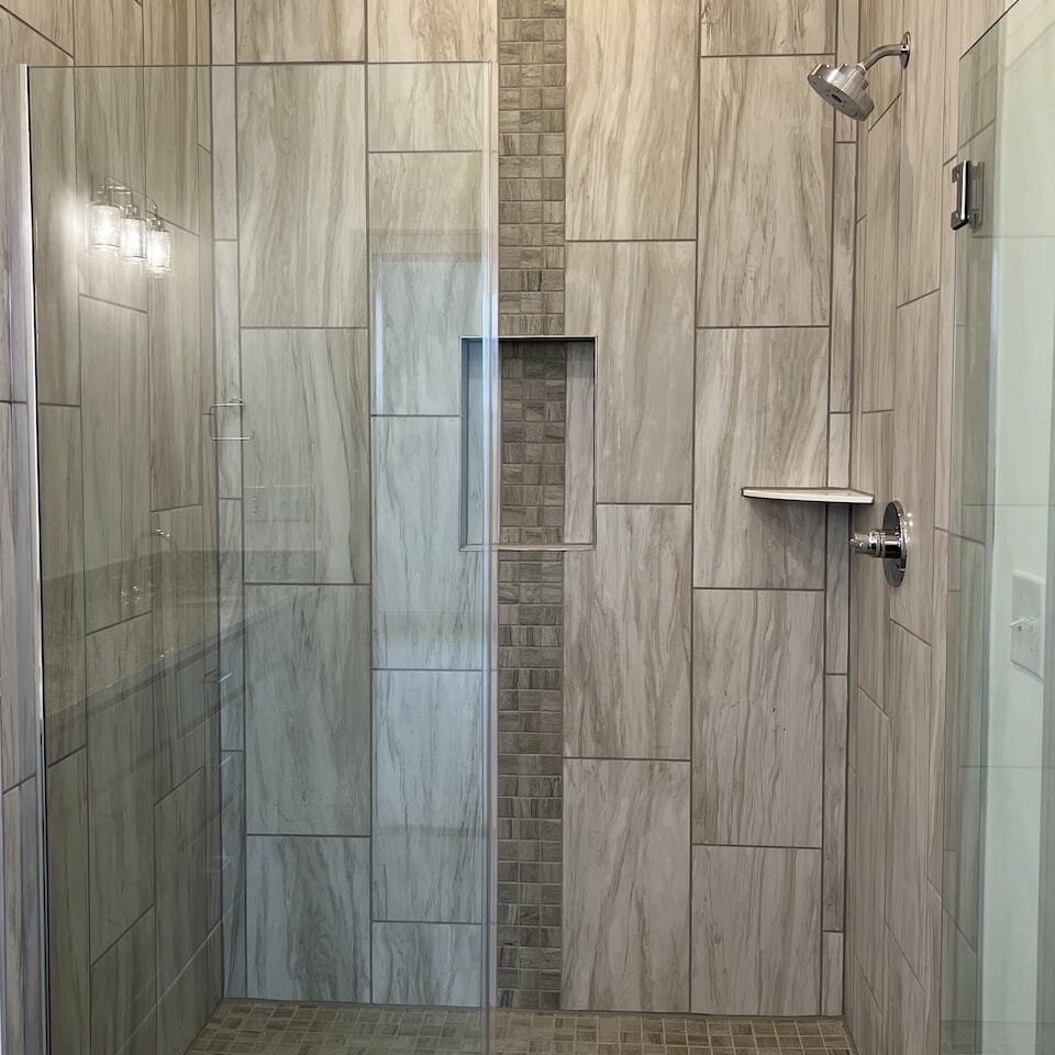 A bathroom with a glass shower door and tiled walls, located in Carmel Indiana.