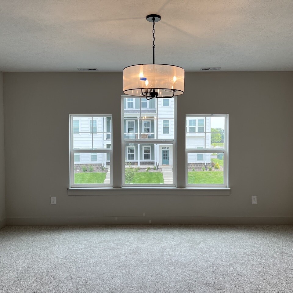 An empty room with a chandelier and windows, built by a luxury custom home builder in Westfield Indiana.