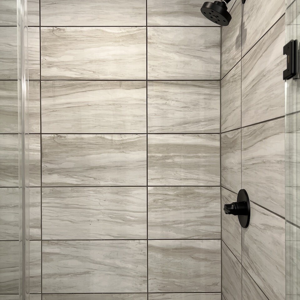 A luxury bathroom with a glass shower door and tiled walls in a custom home built in Carmel, Indiana.