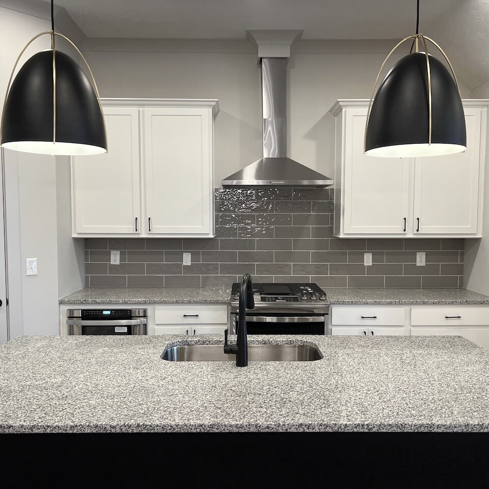 A kitchen with white cabinets and black pendant lights, crafted by a luxury custom home builder in Carmel Indiana.