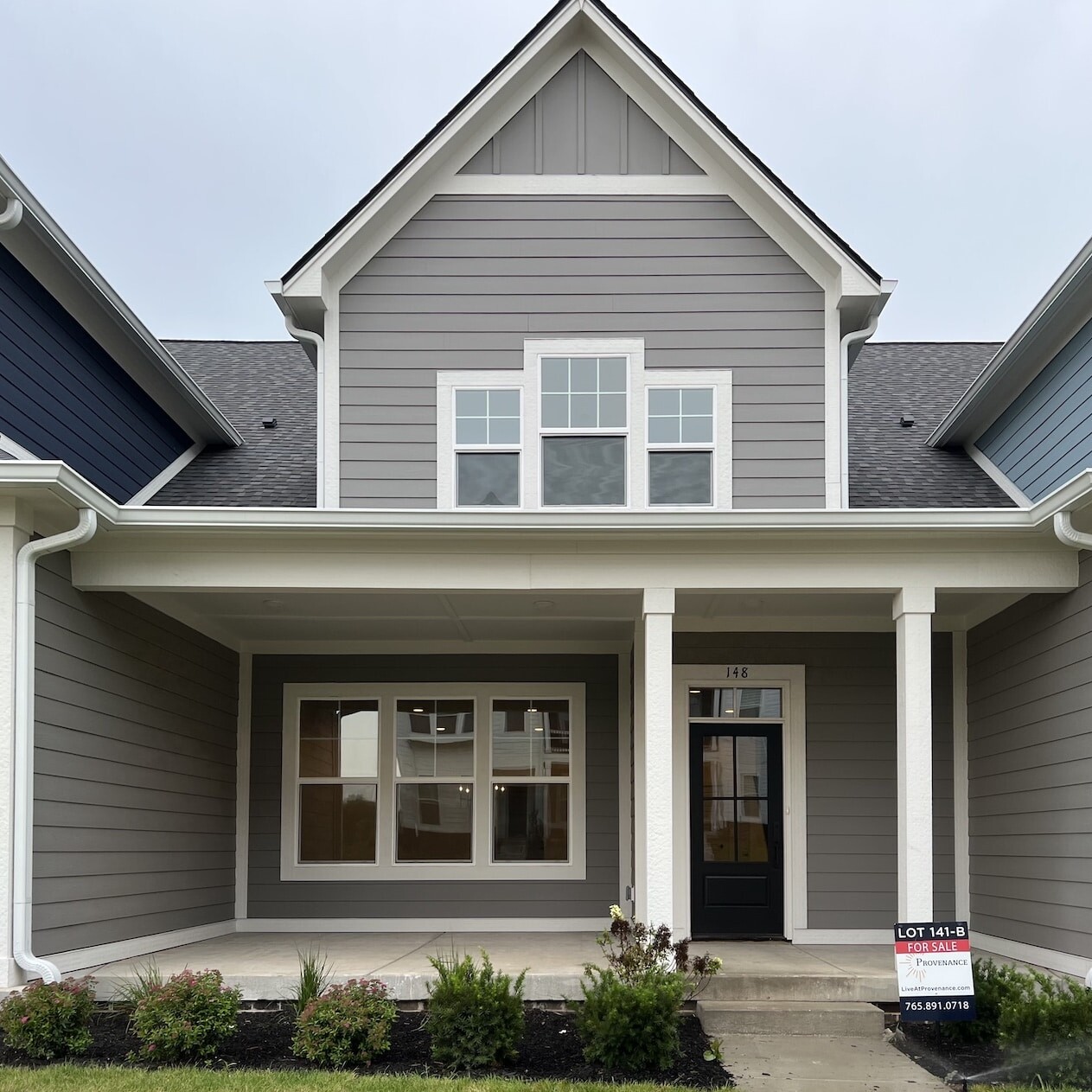 The exterior of a luxury custom home with gray siding and a front porch in Westfield, Indiana.
