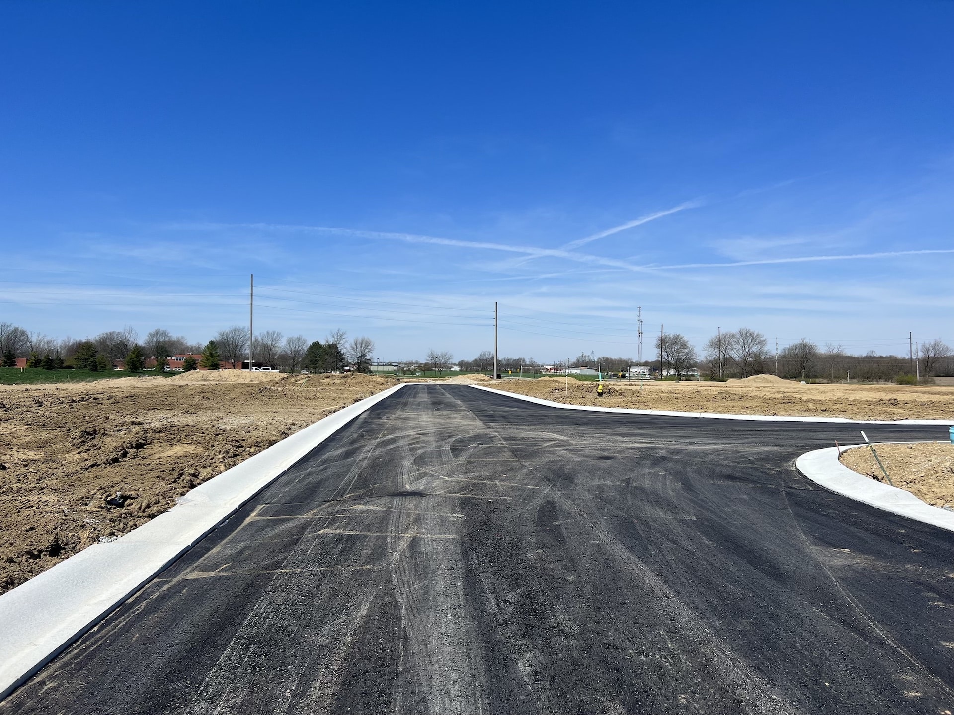 A road is being constructed in the middle of a field, where new homes and custom homes in Westfield, Indiana are being developed nearby.