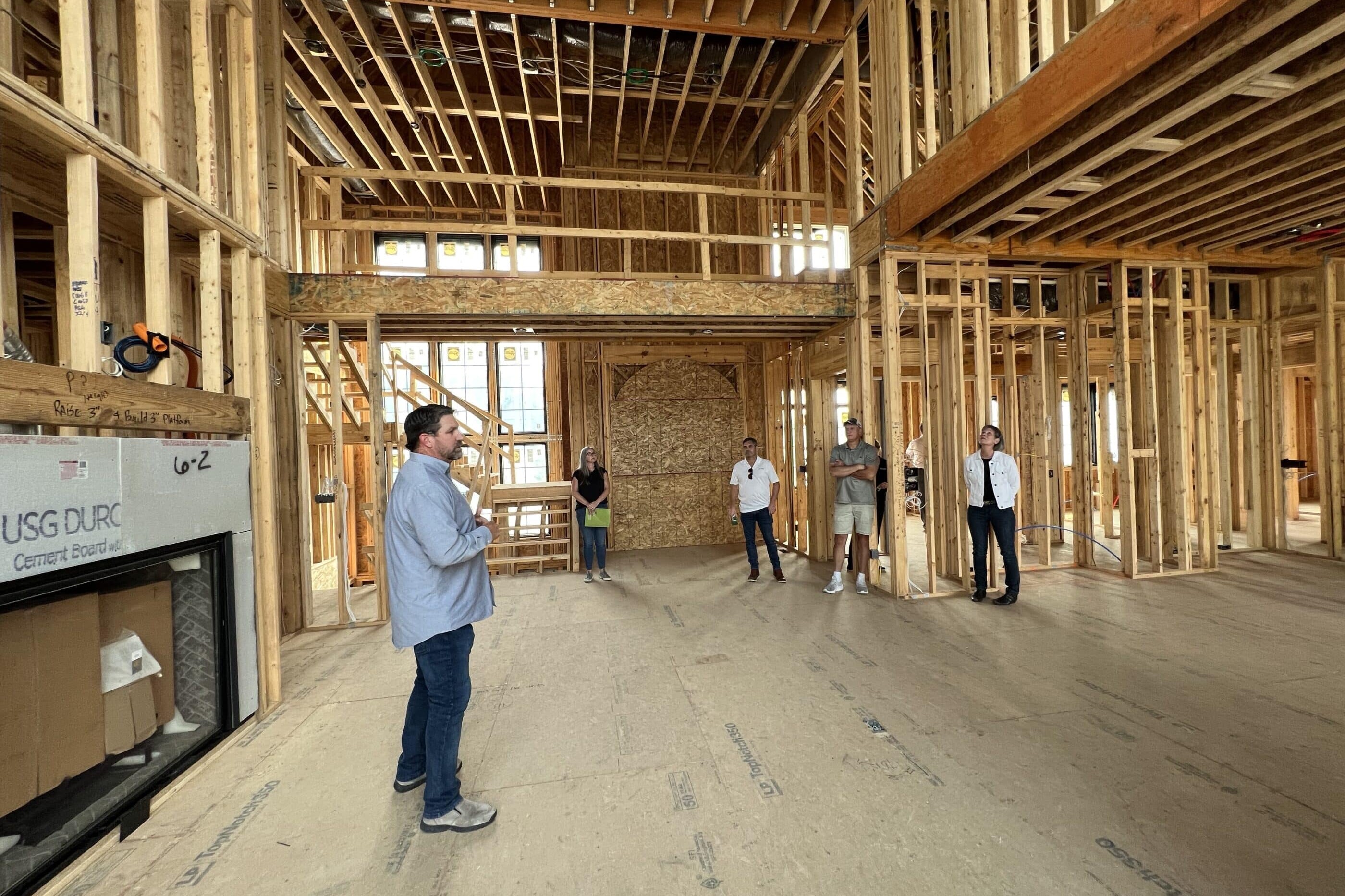 A group of people standing in a house that is under construction, while showcasing the expertise of a Custom Home Builder in Carmel, Indiana.