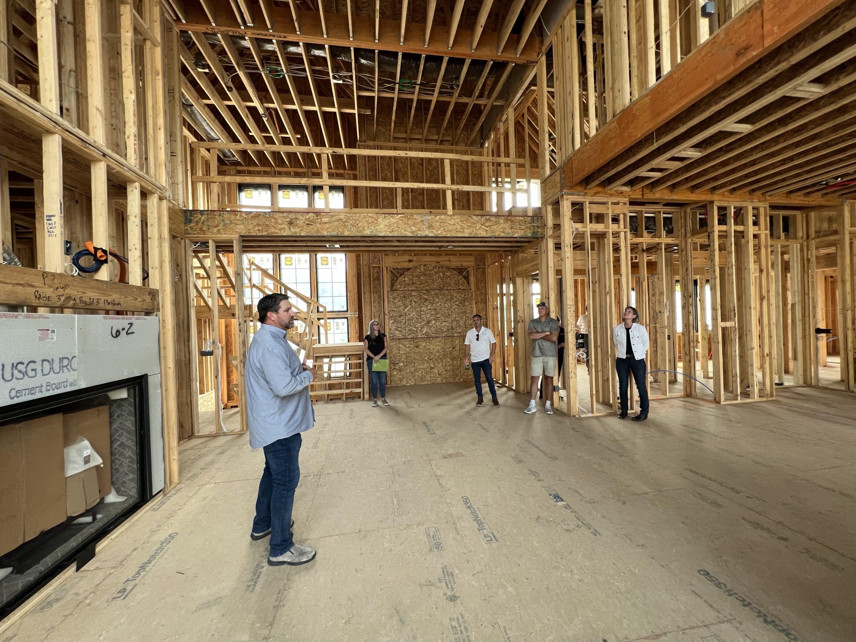 A group of people standing in a house that is under construction, while showcasing the expertise of a Custom Home Builder in Carmel, Indiana.