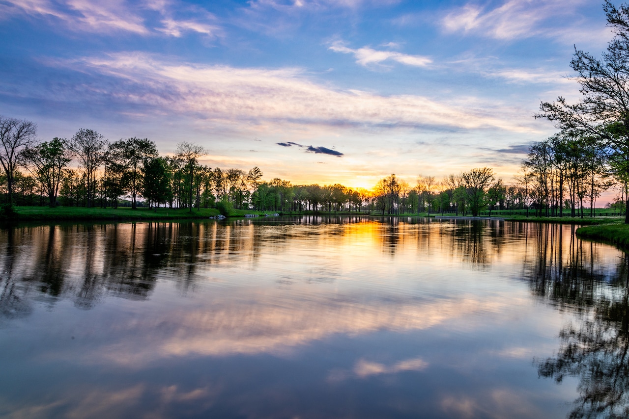 Sunset over a lake with trees in the background.