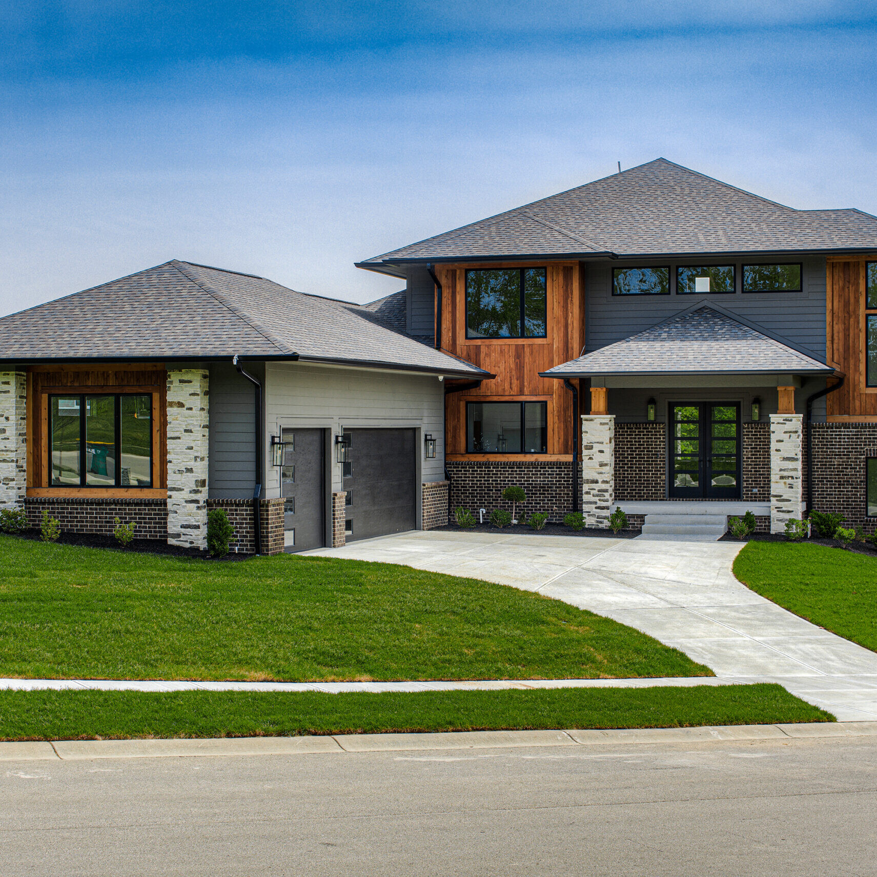 A custom home with a driveway and grass in front of it.