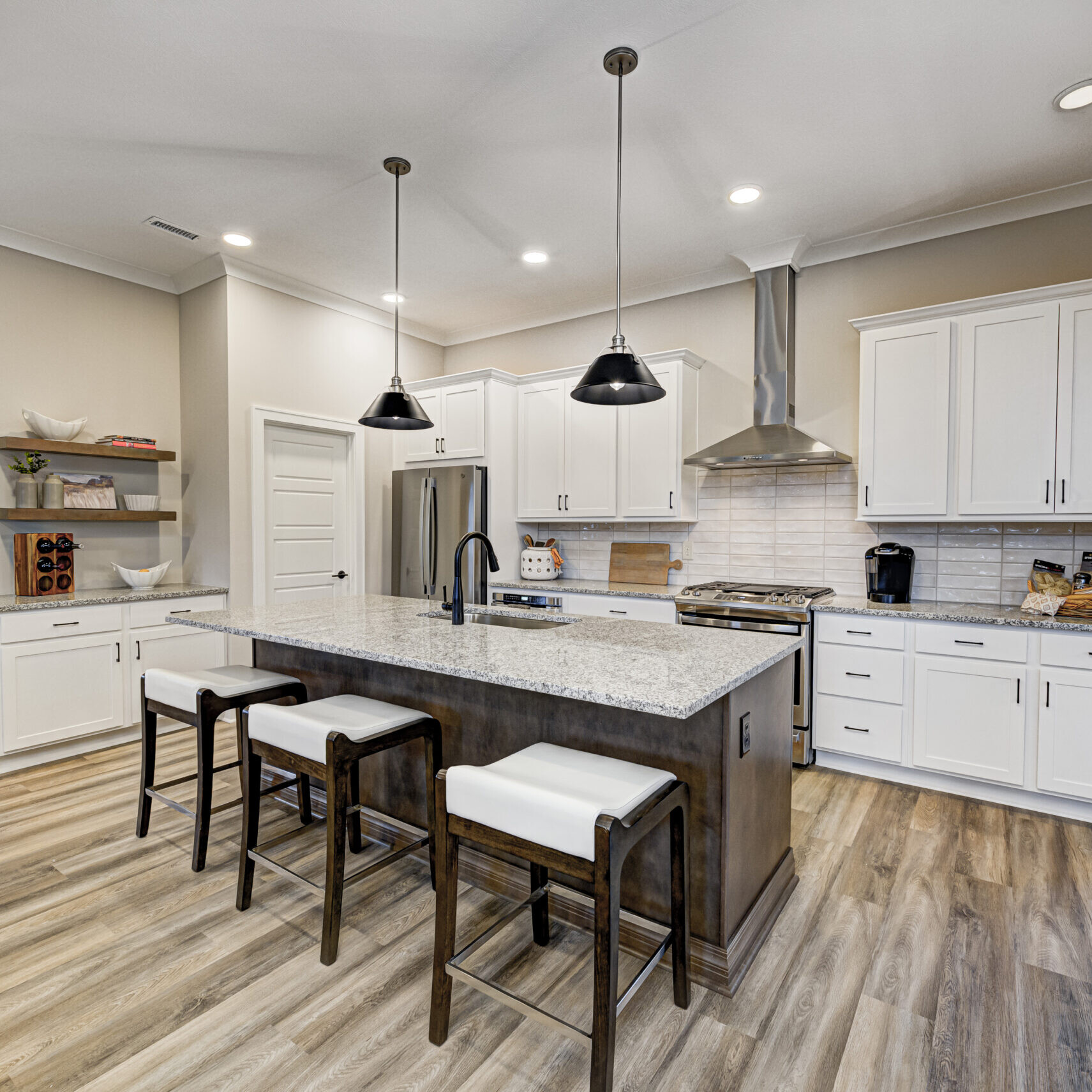 A white kitchen with wood floors and a center island in a custom home.