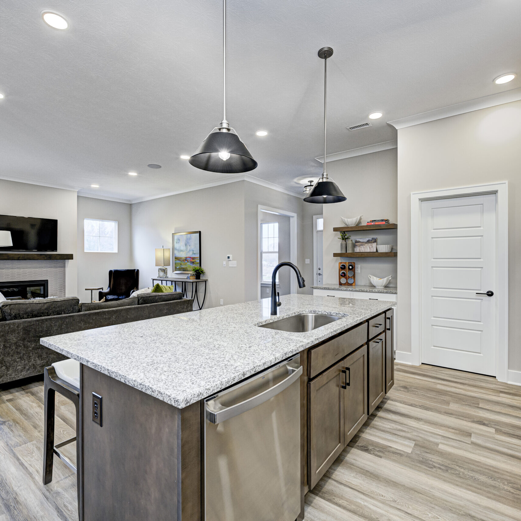 A custom kitchen with hardwood floors and stainless steel appliances in a new home.