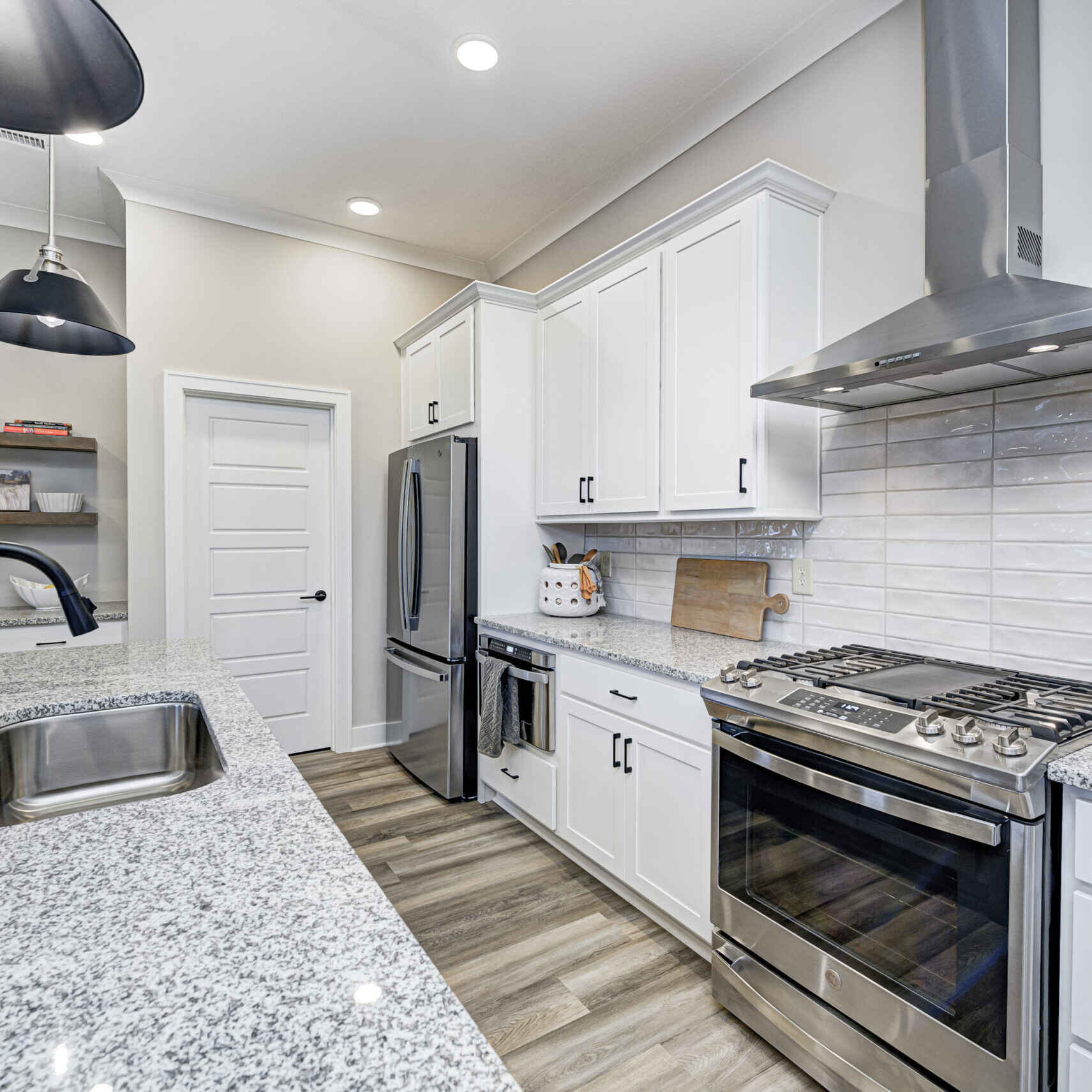 A white kitchen with stainless steel appliances and granite counter tops, designed by a Custom Home Builder in Carmel Indiana.