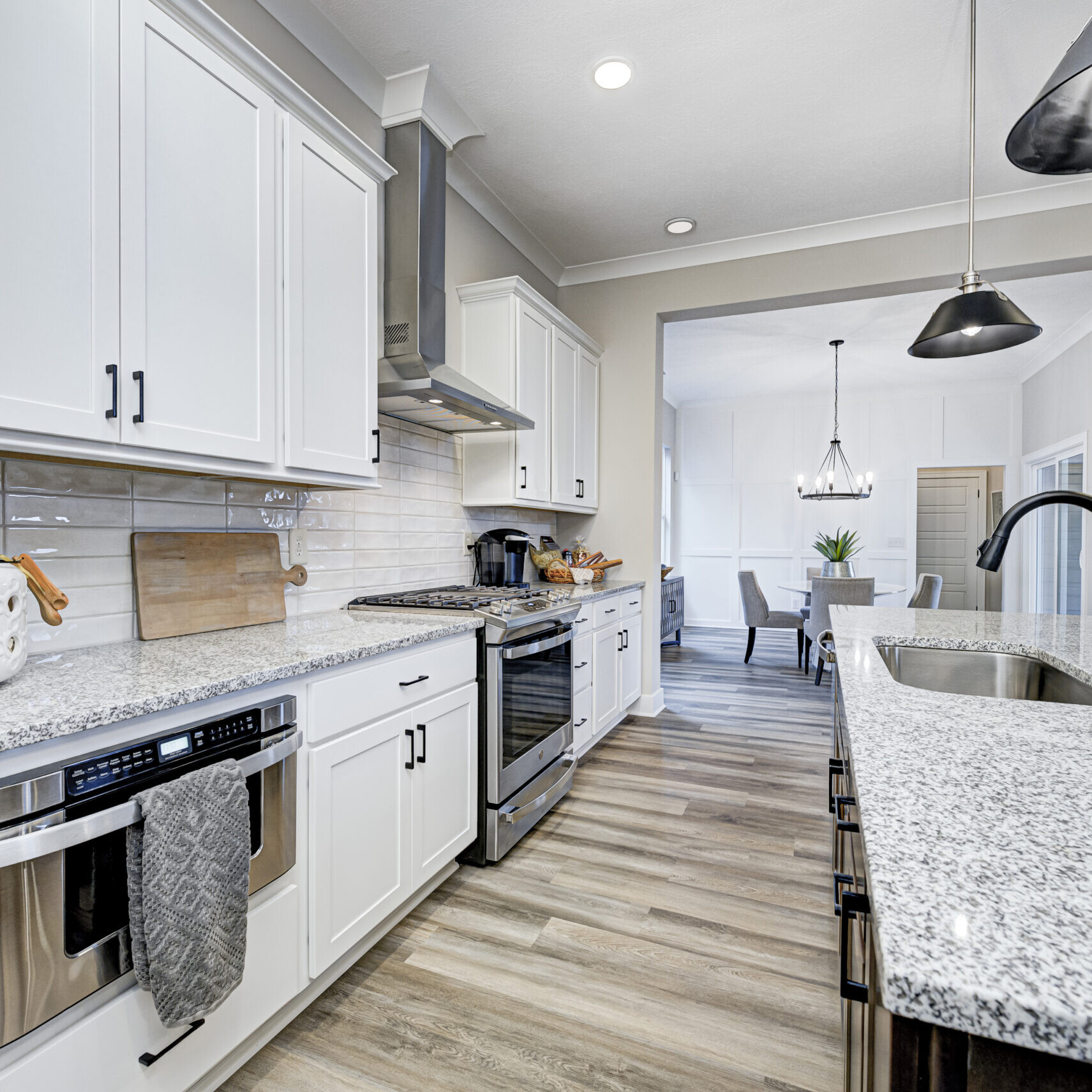 A white kitchen with stainless steel appliances and granite counter tops, custom-built by a reputable home builder in Carmel, Indiana.